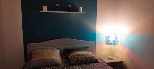 a bedroom with a bed with a blue wall and a lamp at Coquet 2 pièces proche de Paris in Bagnolet