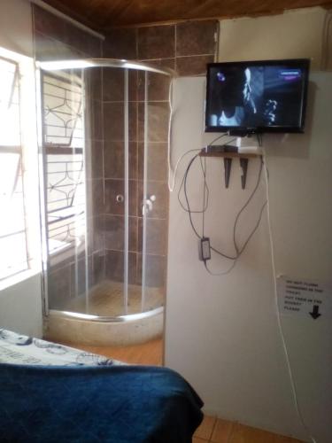 a room with a shower and a television on a wall at Nafi Guesthouse in Phuthaditjhaba