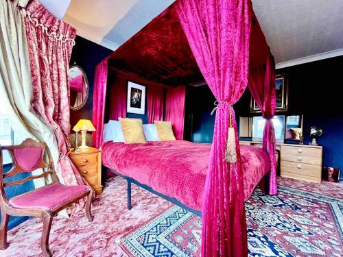 a bedroom with a pink bed with curtains and a chair at The Wizards House York - discounts for long stays in York