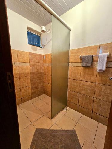 een badkamer met een douche en een glazen deur bij Casa / kitinete in Juiz de Fora