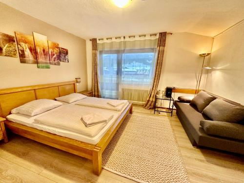 ein Schlafzimmer mit einem Bett und einem Sofa in der Unterkunft Haus Maria in Bruck an der Großglocknerstraße