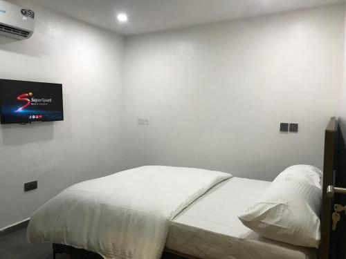 a bedroom with a bed with a tv on the wall at Skenyo Hotel & Apartments in Ketti