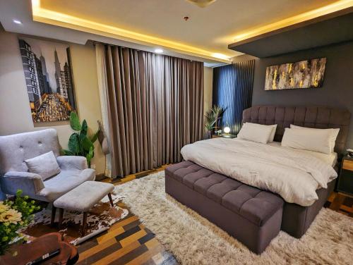 a bedroom with a bed and a couch and a chair at Goldcrest Mall One-bed Penthouse in Lahore