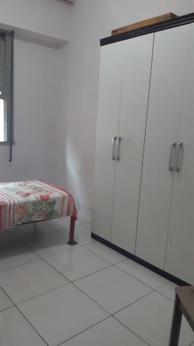 ein weißes Zimmer mit weißen Schränken und einer Bank in der Unterkunft Quarto no Catete in Rio de Janeiro