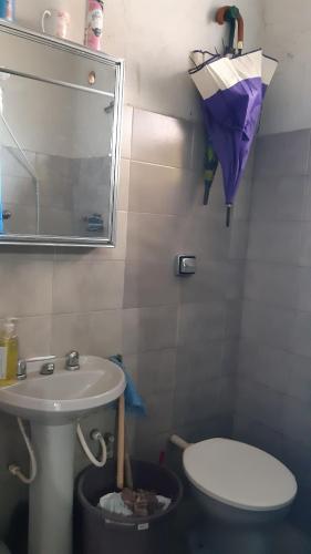 ein Badezimmer mit einem Waschbecken und einem Regenschirm an der Wand in der Unterkunft Quarto no Catete in Rio de Janeiro