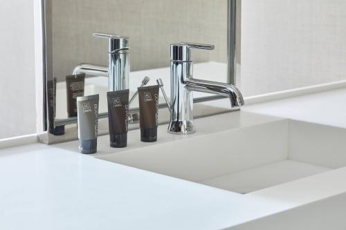 un lavandino in bagno con due rubinetti e uno specchio di AC Hotel by Marriott Raleigh North Hills a Raleigh