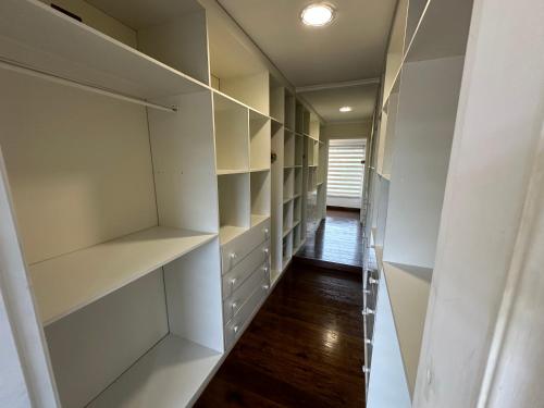 a walk in closet with white shelves and wood floors at Acogedora Casa con Tinaja y Jacuzzi y RENT A CAR in Puerto Varas