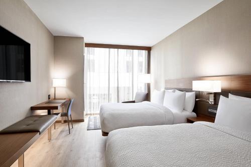 una camera d'albergo con 2 letti, una scrivania e una TV di AC Hotel by Marriott Raleigh North Hills a Raleigh