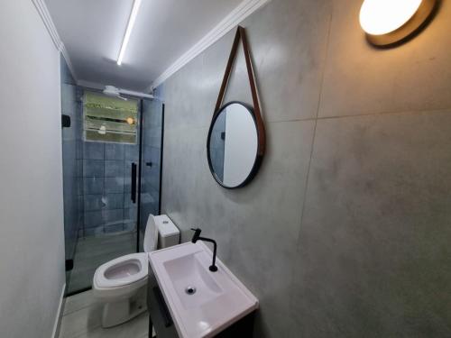 uma casa de banho com um lavatório, um espelho e um WC. em LOFT MUNDI - Conforto no Centro com Ar Condicionado em Águas de Lindoia