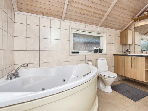 a bathroom with a white tub and a toilet at Holiday home Ebeltoft CXXXVI in Ebeltoft