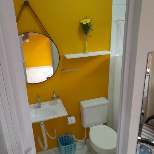 a bathroom with a toilet and a sink and a mirror at Pousada Anjos - à 2 quadras do mar in Matinhos