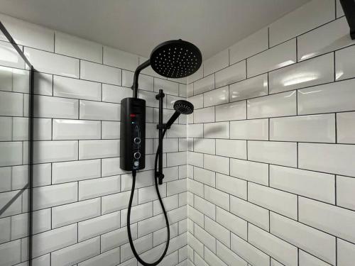 a shower in a white tiled bathroom at Ultra Modern Studio Apartment, in Central Exeter in Exeter