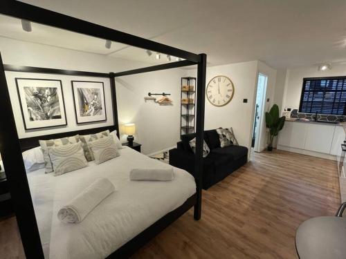a bedroom with a black canopy bed and a clock at Ultra Modern Studio Apartment, in Central Exeter in Exeter