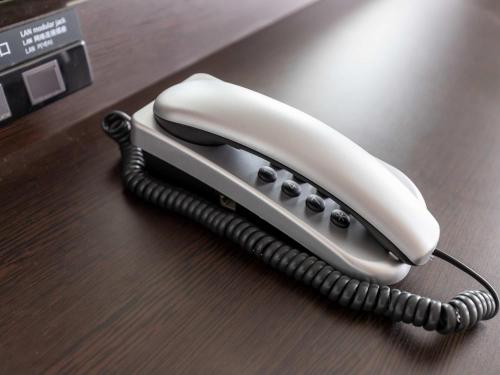 a white phone sitting on a wooden table at APA Hotel Kyoto Eki Horikawadori in Kyoto