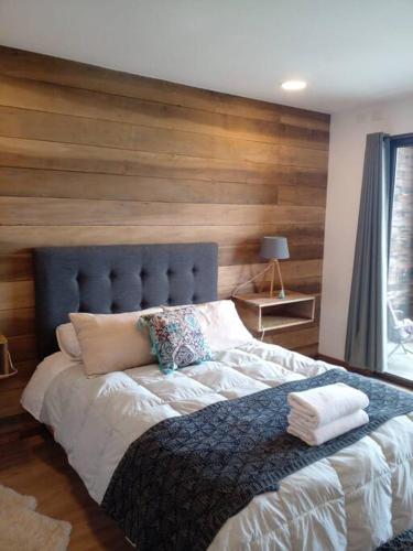 1 dormitorio con 1 cama grande y pared de madera en Acogedor en parcela, en Llanquihue