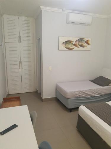 a bedroom with two beds and a table and a desk at Flat com serviços na Riviera in Bertioga