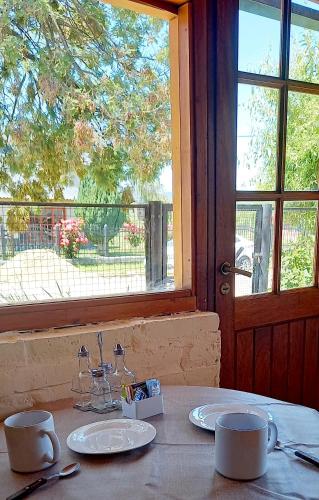 a table with two cups and plates and a window at Departamento Anita in El Hoyo