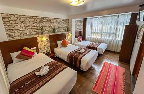 a hotel room with three beds and a brick wall at Hotel Machupicchu Adventure in Machu Picchu