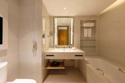 a bathroom with a sink and a tub and a toilet at Four Points by Sheraton Shenzhou Peninsula Resort in Wanning