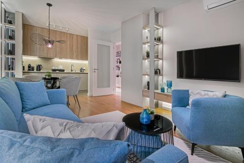 a living room with blue chairs and a tv at Melody Apartment in Novi Beograd