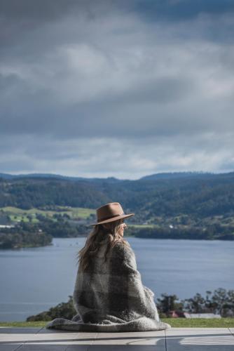 a person in a blanket looking at a lake at Villa Talia Tasmania in Wattle Grove