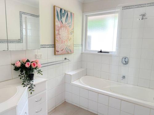 La salle de bains blanche est pourvue d'une baignoire et d'un lavabo. dans l'établissement Shine Carrum Down - Family Oasis In A Tranquil Court, à Carrum Downs