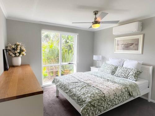 een witte slaapkamer met een bed en een raam bij Shine Carrum Down - Family Oasis In A Tranquil Court in Carrum Downs