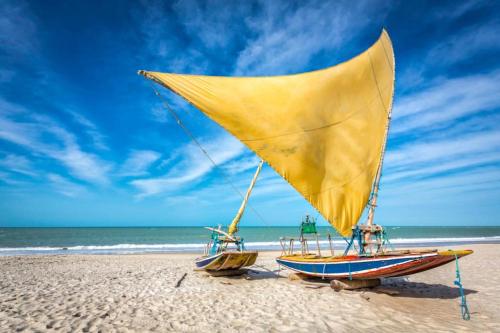 two boats on a beach with a yellow sail at Premium Flats - Tulip Inn in Fortaleza