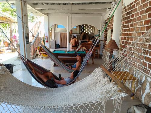 a group of people laying in hammocks in a room at Munay Backpacker Hostel in Montañita