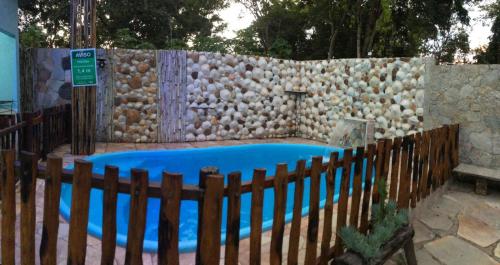 a swimming pool with a fence and a stone wall at Casadabiquinha in Pirenópolis