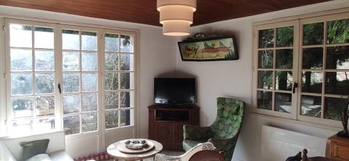 sala de estar con ventanas, mesa y sillas en Ancienne Bergerie au cœur de la nature dans le parc du Vercors., en Rencurel