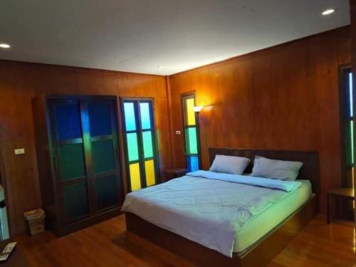 a bedroom with a bed with wooden walls and windows at Rai Phuchat in Ban Pa Thon
