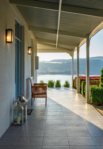 a porch with a bench and a view of the water at Villa Talia Tasmania in Wattle Grove