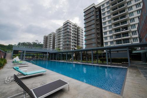 una piscina con 2 sillas y algunos edificios en BB Condo Homestay, en Sandakan