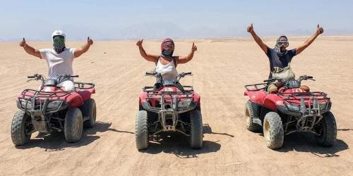 PYRAMIDS TOWER Inn في القاهرة: ثلاثة أشخاص في atvs في الصحراء بيديهم فوق