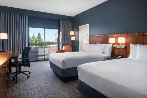 a hotel room with two beds and a desk at Courtyard by Marriott Phoenix Airport in Phoenix