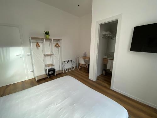 a white bedroom with a bed and a desk and a tv at Belltower Elegans Guest House in Rome