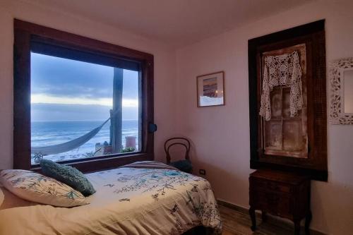 a bedroom with a window with a view of the ocean at Hogar mágico en Punta de Choros in Choros