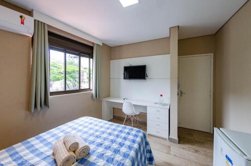 1 dormitorio con cama, escritorio y ventana en STUDIOS CORACAO EUCARISTICO, en Belo Horizonte