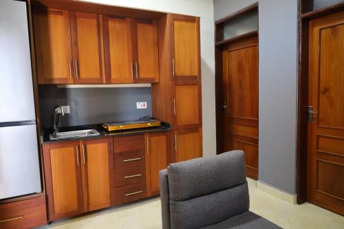 Habitación con silla y cocina con armarios de madera. en Morris Multi en Dar es Salaam