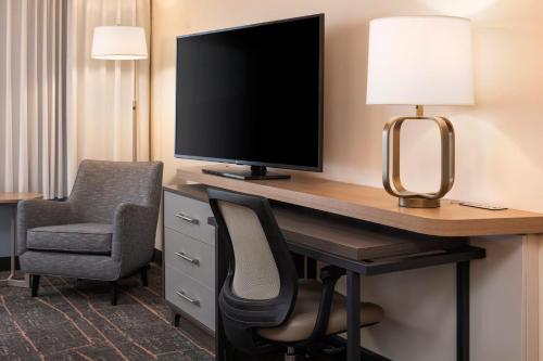 a room with a desk with a television and a chair at Holiday Inn Hotel & Suites Maple Grove Northwest Minneapolis-Arbor Lakes by IHG in Maple Grove