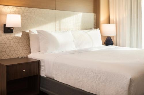 a bedroom with a large bed with white sheets and pillows at Holiday Inn Hotel & Suites Maple Grove Northwest Minneapolis-Arbor Lakes by IHG in Maple Grove