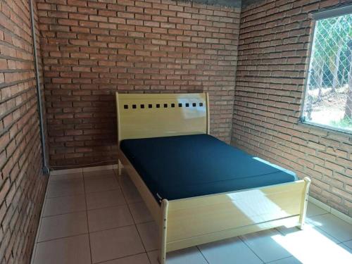 um pequeno quarto com uma cama numa parede de tijolos em Casa de Campo Trevão - Queluzito em Conselheiro Lafaiete