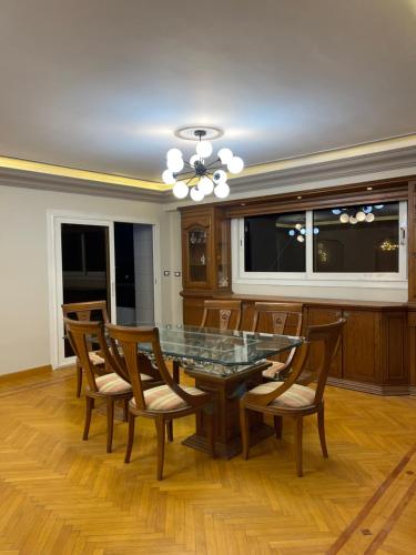 uma sala de jantar com uma mesa de vidro e cadeiras de madeira em Elegant Apartment no Cairo
