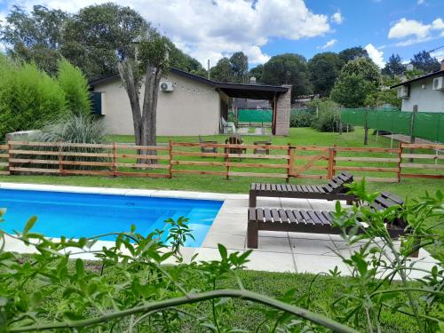 um banco ao lado de uma cerca e uma piscina em Chalet El Buho em Villa General Belgrano