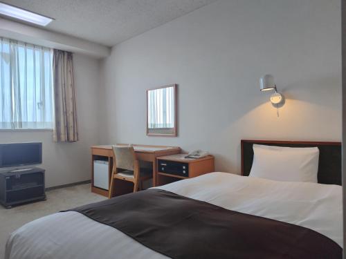 新庄市にあるニューグランドホテルのベッド、デスク、コンピュータが備わるホテルルームです。