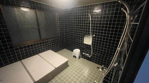 a black tiled bathroom with a toilet and a shower at Iimori Vista in Hakuba