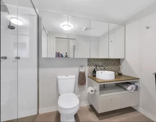 La salle de bains blanche est pourvue de toilettes et d'un lavabo. dans l'établissement Light apartment in amazing central location, à Brisbane