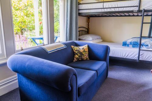 Halfmoon Cottage في أكارو: غرفة معيشة مع أريكة زرقاء وسرير بطابقين