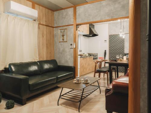 a living room with a black leather couch and a table at 駅徒歩1分 静かな阿倍野の一棟貸し 長期滞在向け 最大6名 Tsubame INN Abeno in Osaka
